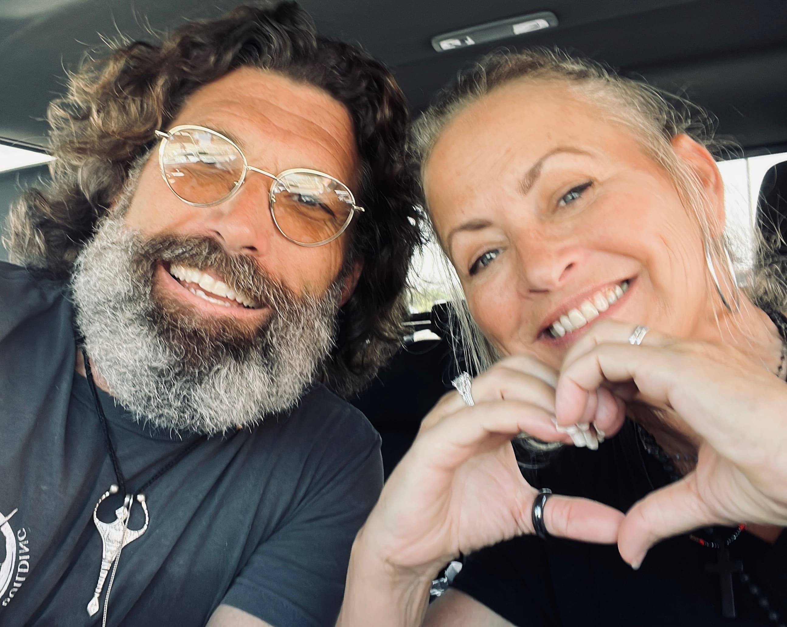 Jason and Gina smiling together, forming a heart with their hands
